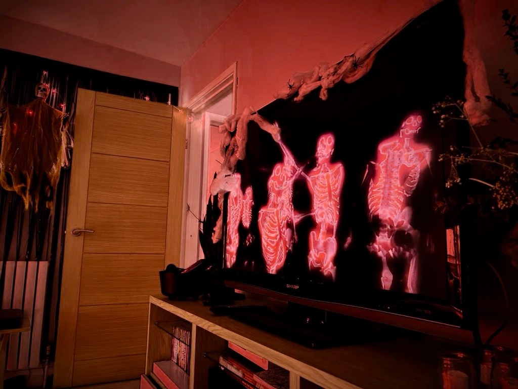 Glowing dancing skeletons on a television screen, framed with cobwebs and plastic spiders