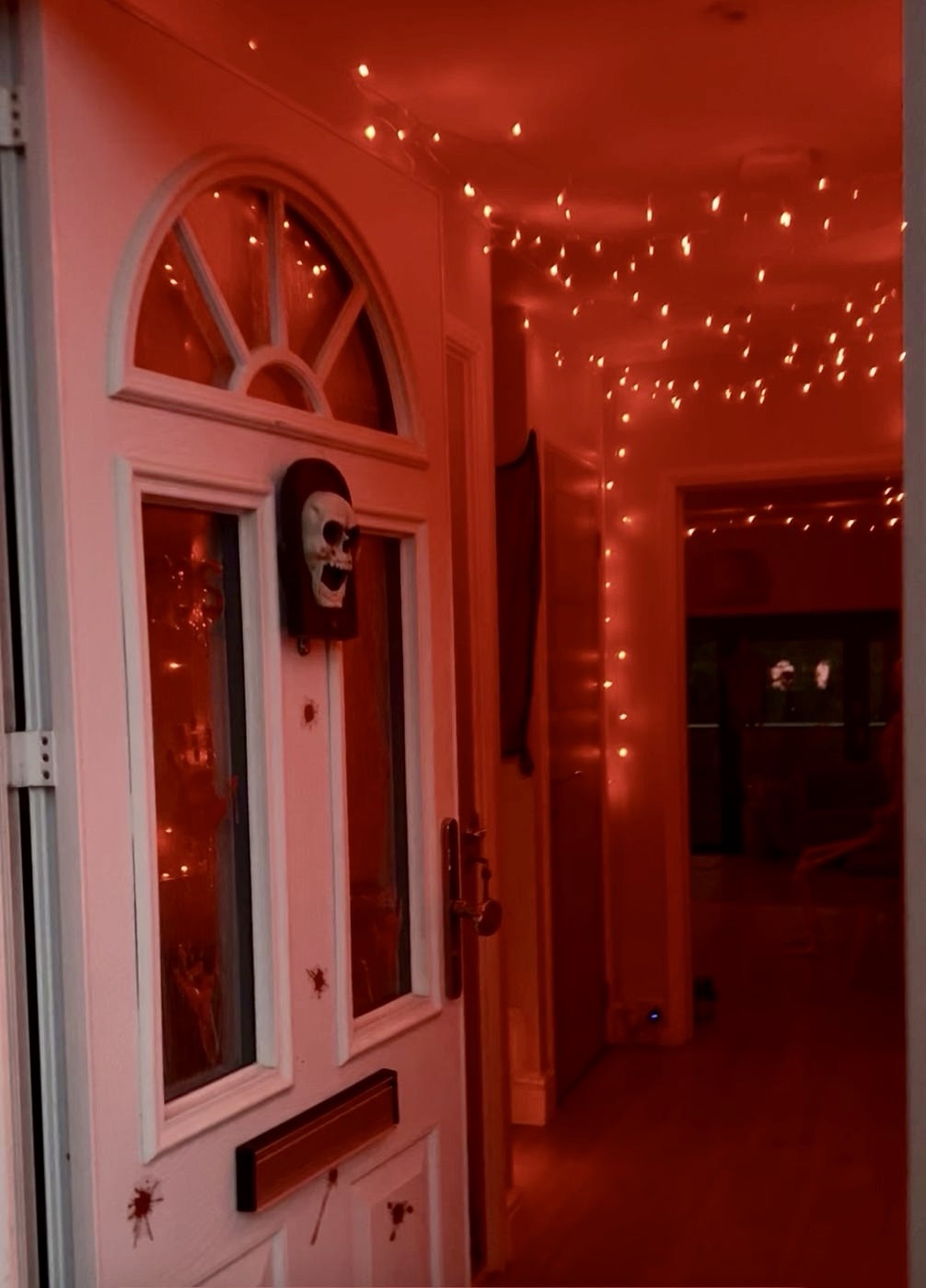 The front door open onto a hallway strung with fairy lights, with a skull door knocker